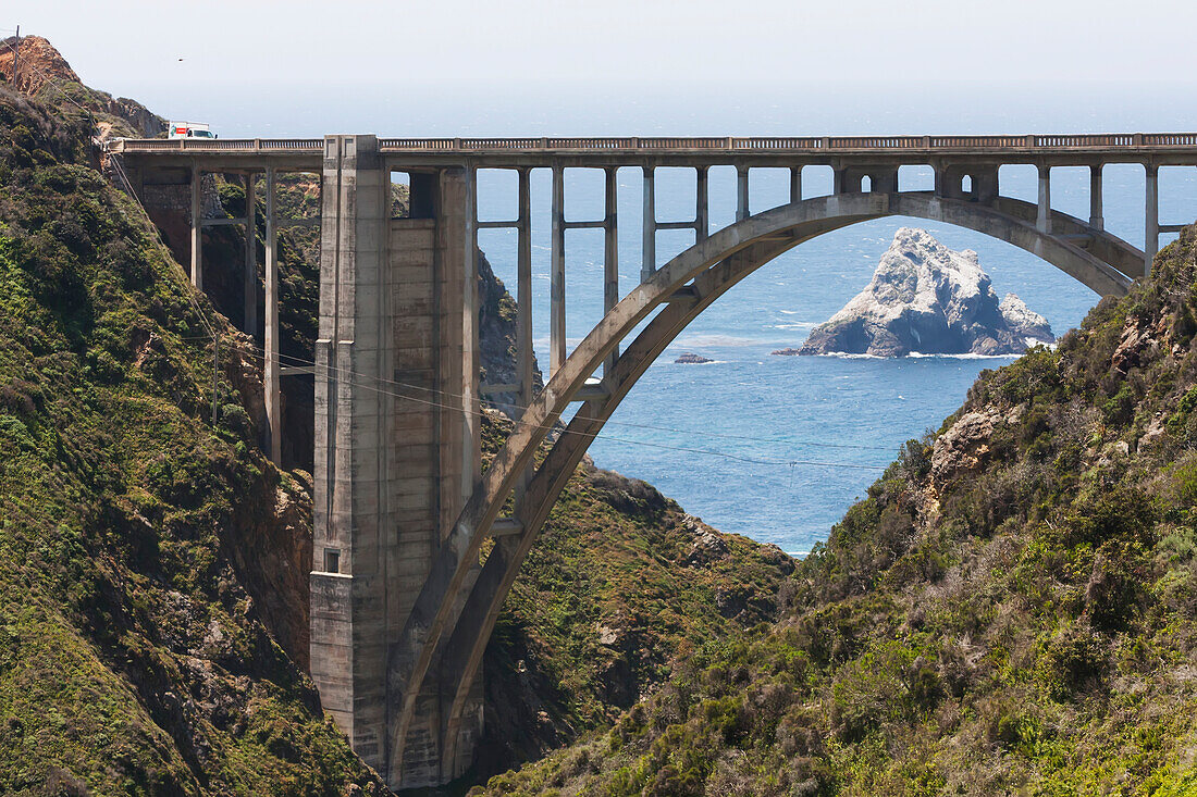 Straßenbrücke über die zerklüftete Küste mit einer Felsformation im Meer; Kalifornien, Vereinigte Staaten von Amerika