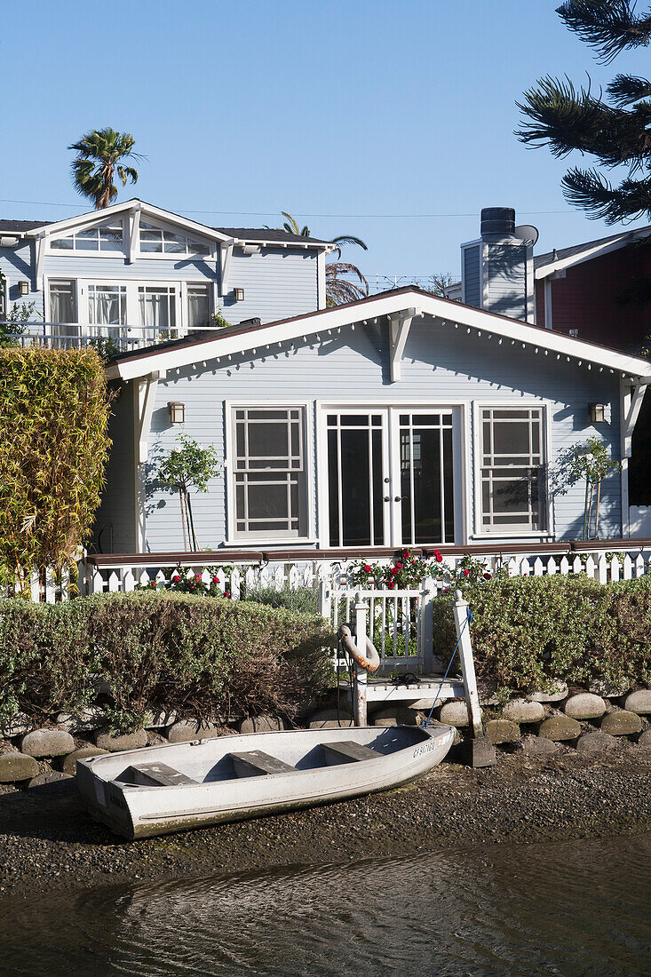 A House Along The Water With A Canoe On The Rocky Shore; California, United States Of America