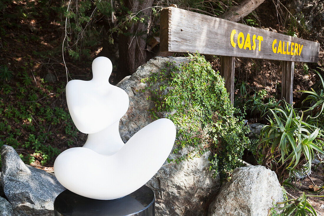 A Sculpture Beside A Wooden Sign For Coast Gallery; California, United States Of America