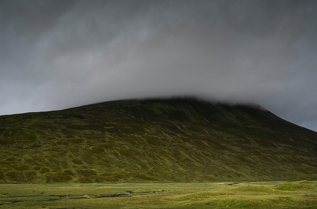 UK, Scotland, Storm clouds covering green hill