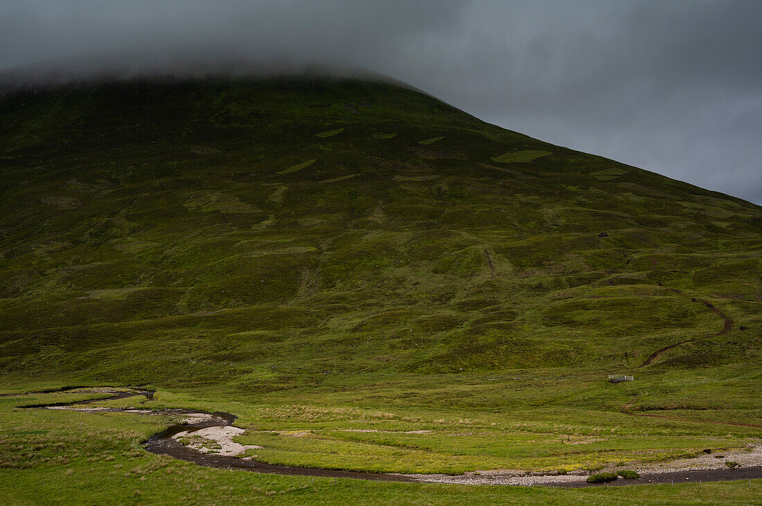 UK, Schottland, Gewitterwolken über grünem Hügel