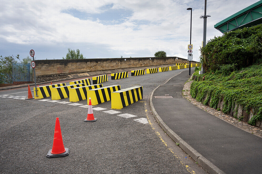 Yellow and black striped road traffic barricades and traffic cones on road