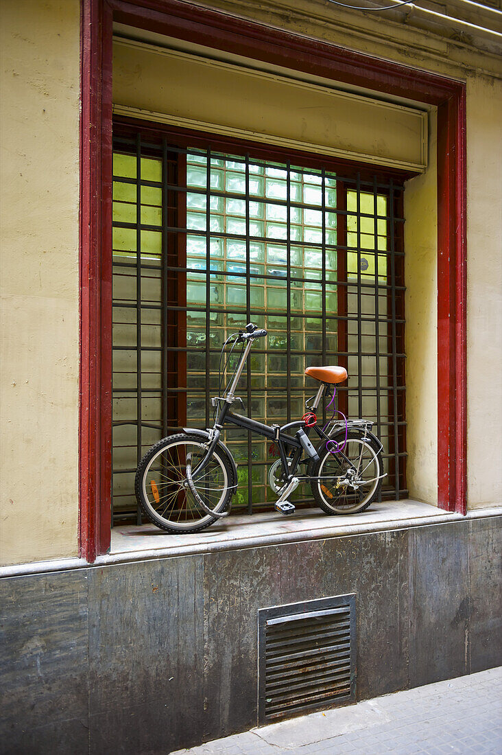 A Bicycle Parked Outside A Window With Red Trim; Barcelona, Spain