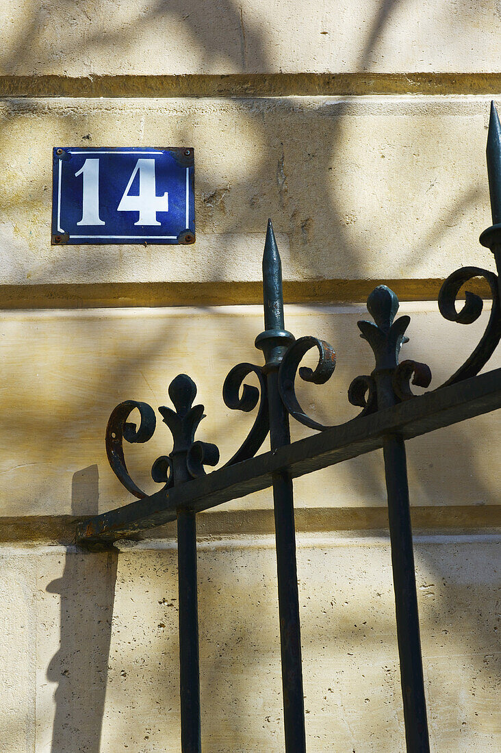 Schild Nummer vierzehn und ein verziertes Geländer an einem Gebäude, Marais-Viertel; Paris, Frankreich.