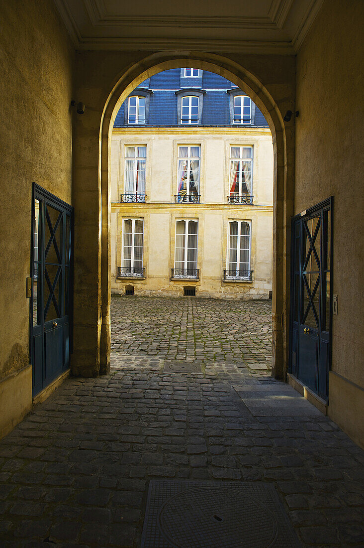 A Covered Walkway With An Arched Entrance And Doorways, Marais District; Paris, France