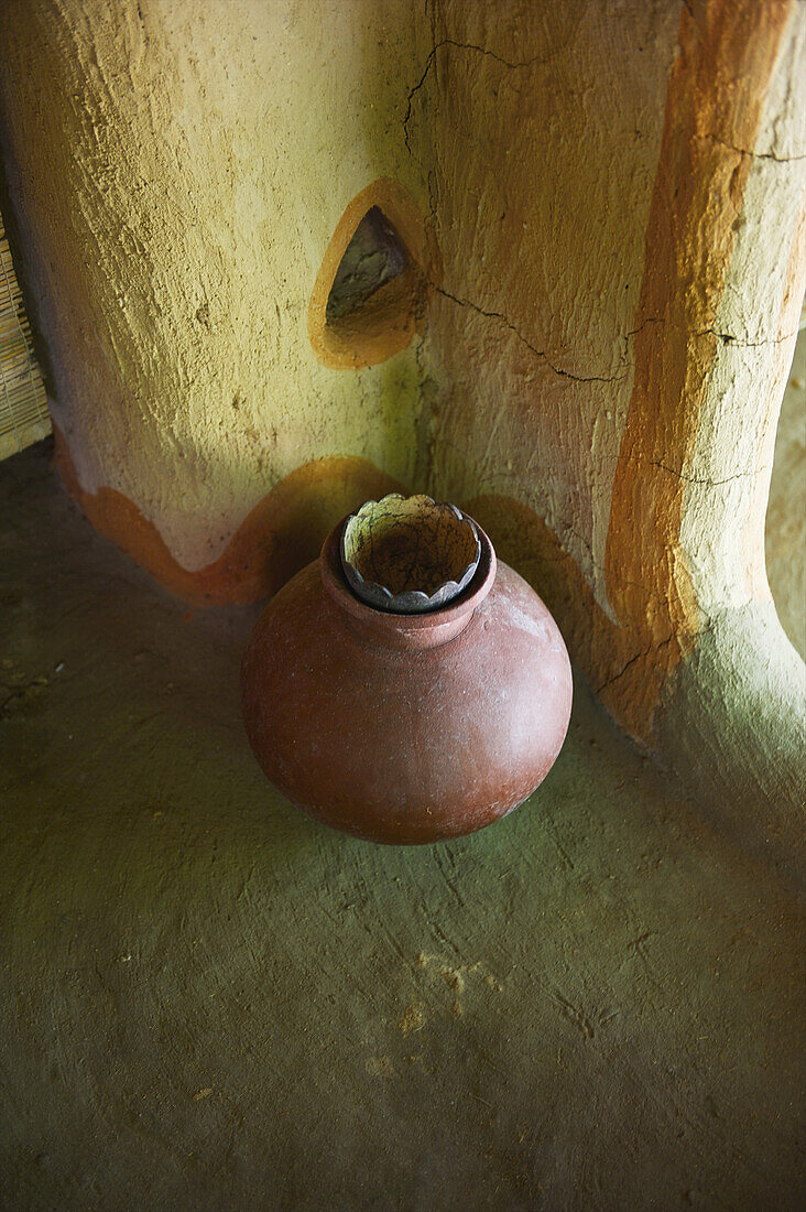 Ein Tonkrug steht gegen eine rissige Innenwand; Ulpotha, Embogama, Sri Lanka.