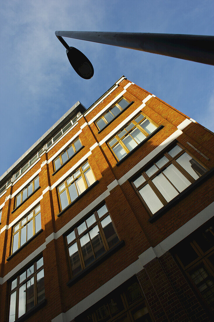 Niedriger Blickwinkel auf ein braunes Backsteingebäude, Straßenlicht und blauer Himmel, Shoreditch; London, England