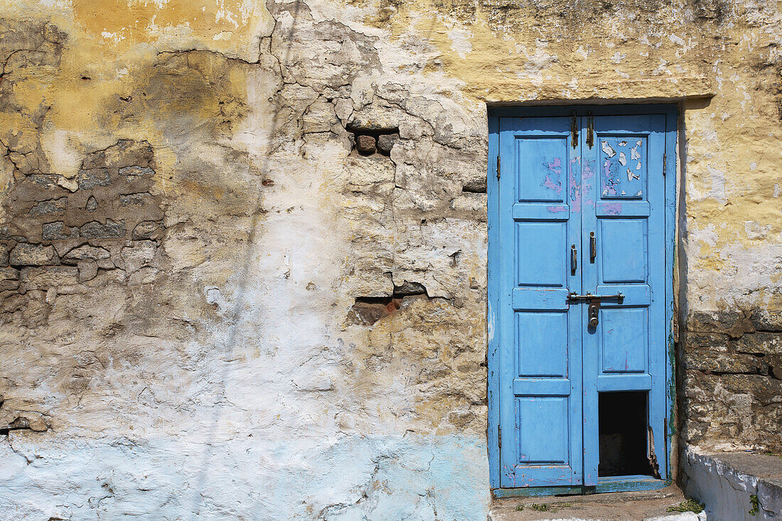 An Old, Broken Blue Door Along A Cracked Wall; Hampi, Karnataka, India