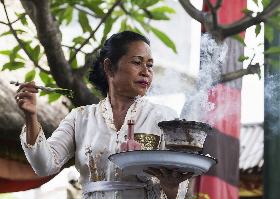 Priesterin trägt Weihrauch und Wasser in einer Barong-Tanzvorführung in Batubulan, Bali, Indonesien