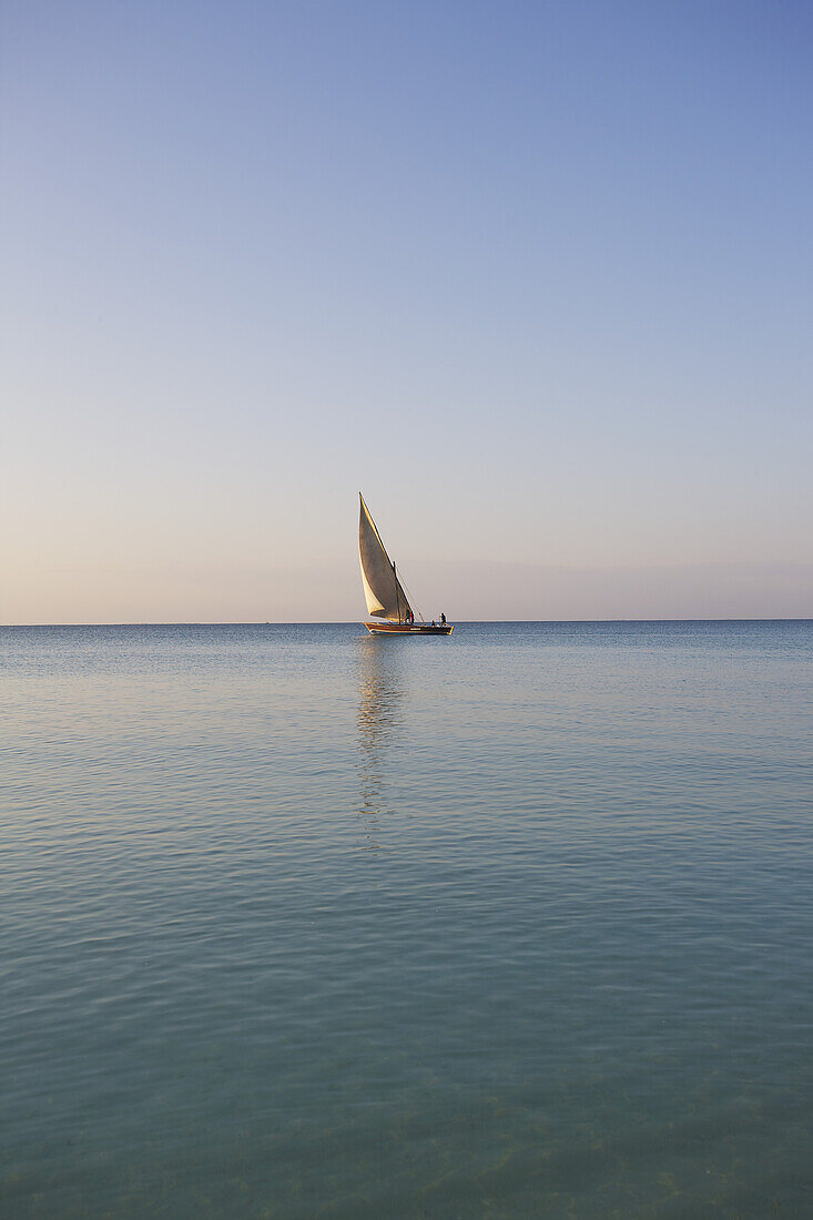 A Sailboat In The Distance On The Tranquil Water Of The Indian Ocean; Vamizi Island, Mozambique