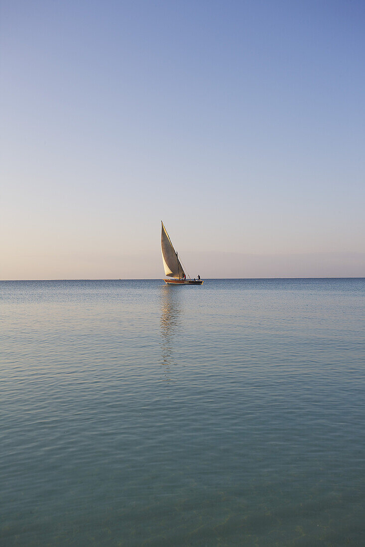 Ein Segelboot in der Ferne auf dem ruhigen Wasser des Indischen Ozeans; Vamizi-Insel, Mosambik