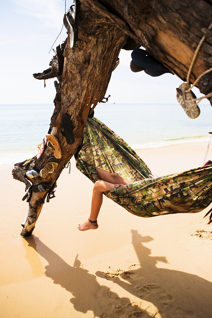 Ausruhen in einer Hängematte in einem mit verlorenen Flip Flops geschmückten Baum; Sihanoukville, Kambodscha