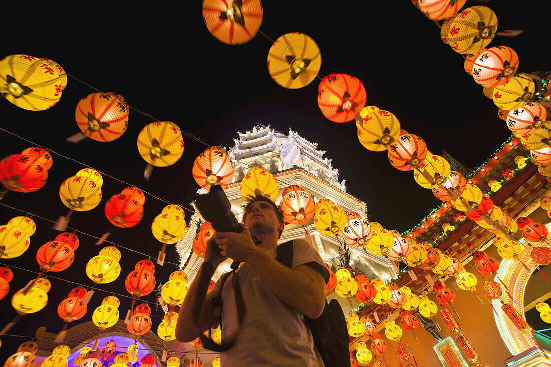 Die fantastische Beleuchtung des Kek Lok Si Tempels und ein Tourist mit einer Kamera; Penang, Malaysia