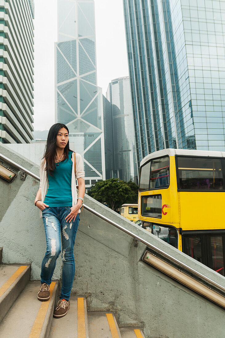 Chinesische junge Frau mit dem Gebäude der Bank of China im Hintergrund; Hongkong, China