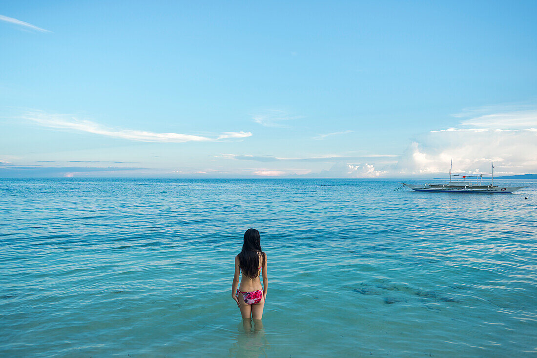 Eine junge Frau watet im Wasser vor dem Alona Beach; Panglao Island, Bohol, Philippinen
