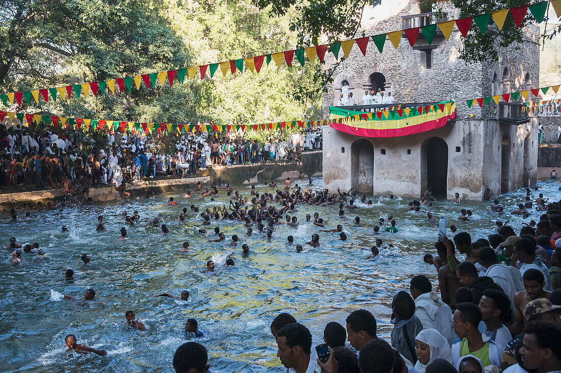 Äthiopisch-orthodoxe Christen schwimmen im Wasser bei einer in den Fels geschlagenen Kirche in Timkat; Lalibela, Äthiopien.