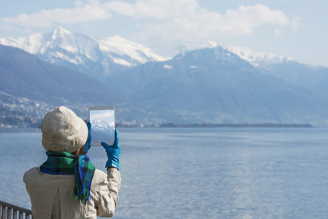 Touristin fotografiert die Schweizer Alpen und den Lago Maggiore mit ihrem Tablet; Brissago, Tessin, Schweiz