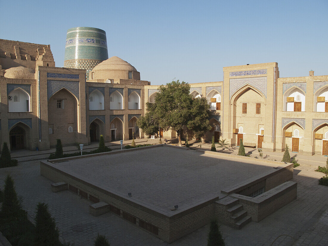 Hof des Hotels Chiwa (ehemals Mohammed Amin Khan Madrassah) und Kalta Minar dahinter, Ichan Kala Altstadt; Chiwa, Usbekistan.