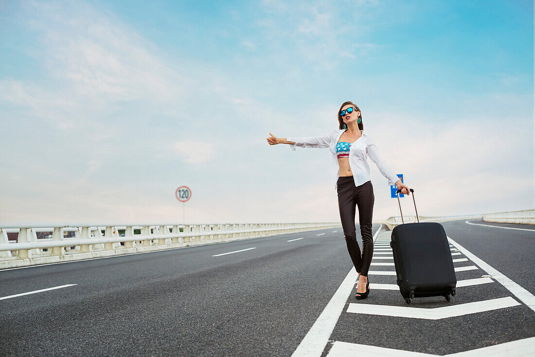 Woman Hitchhiking On A Highway With Her Luggage; Xiamen, Fujian, China