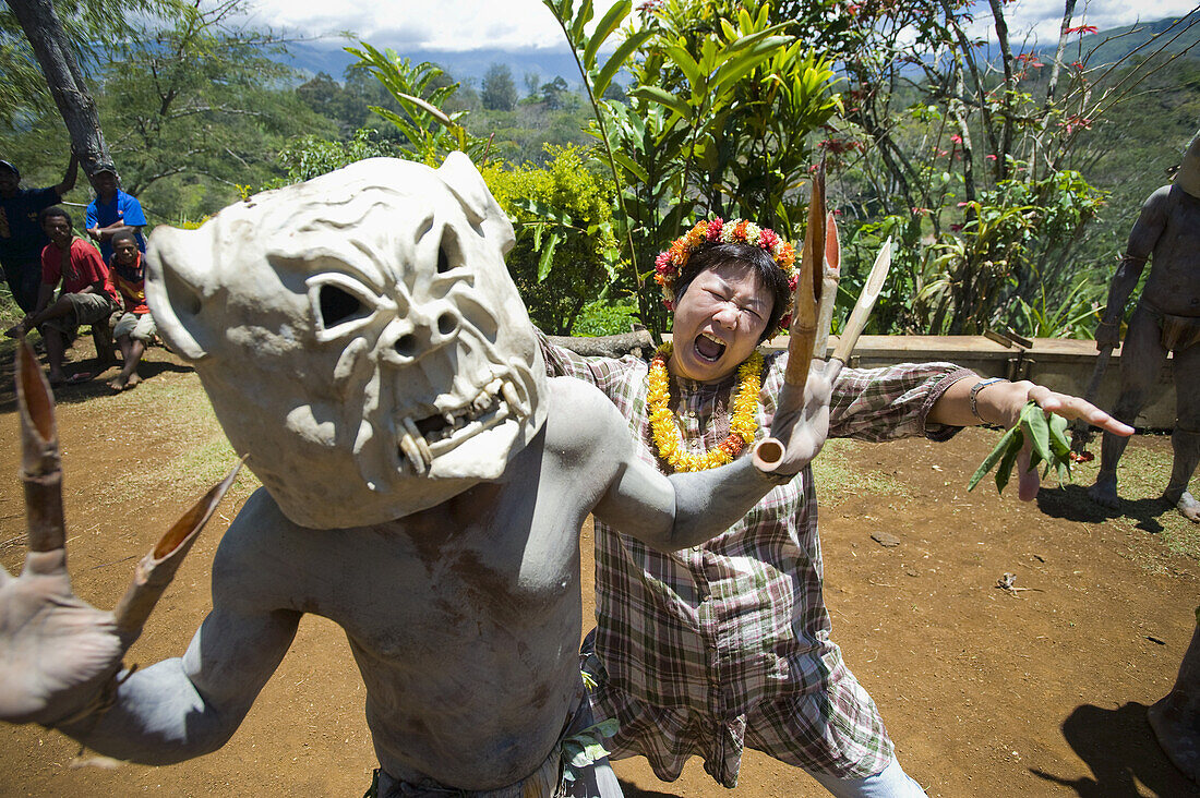 Japanische Frau nimmt an einer Aufführung der Goroka Mudmen teil; Goroka, östliches Hochland, Papua-Neuguinea.