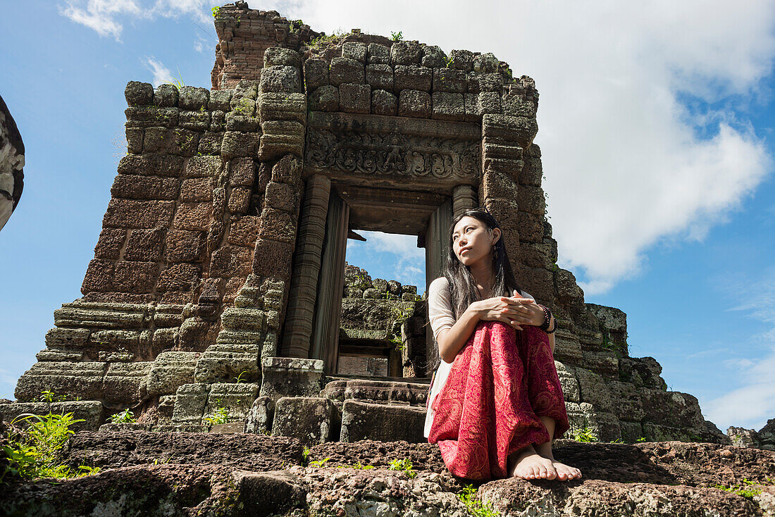 Junge Frau sitzt vor einer Tempelruine, Angkor Wat; Siem Reap, Kambodscha