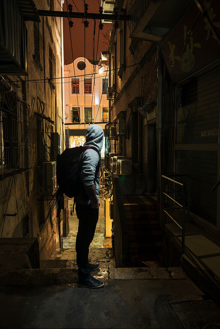 Männlicher Reisender, der eine schmale Straße hinunterblickt; Xiamen, Fujian, China