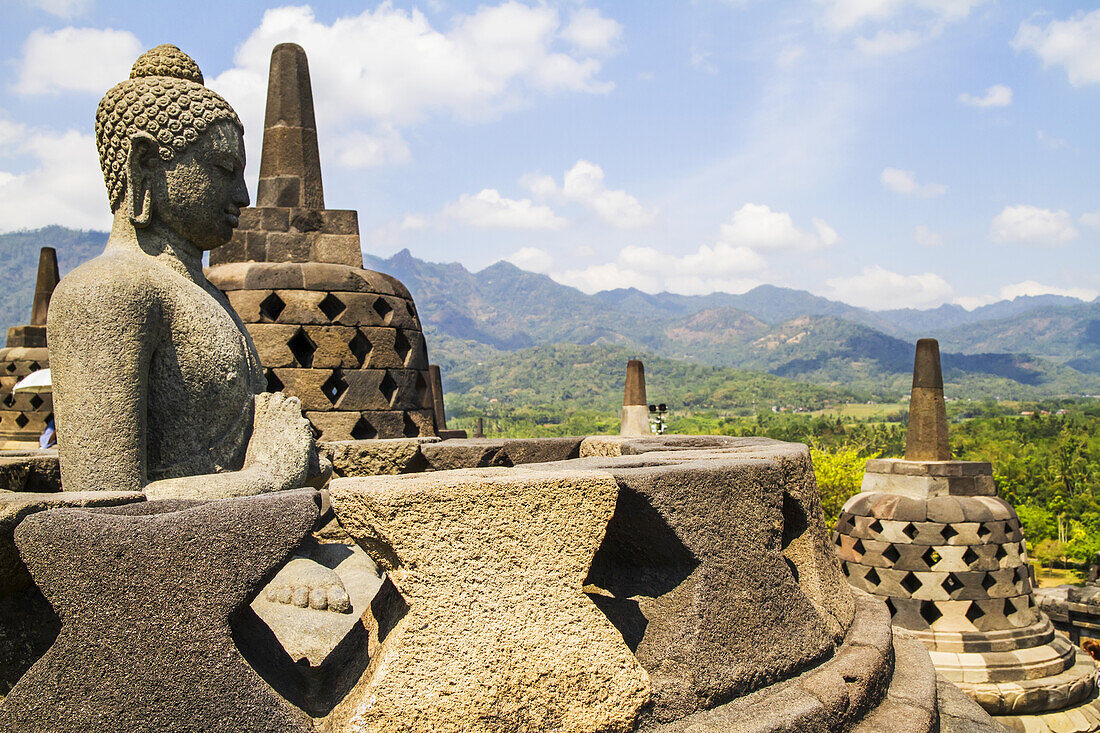 Buddha-Statue inmitten der vergitterten Steinstupas mit Buddha-Statuen auf der oberen Terrasse, Borobudur-Tempelanlage, Zentral-Java, Indonesien