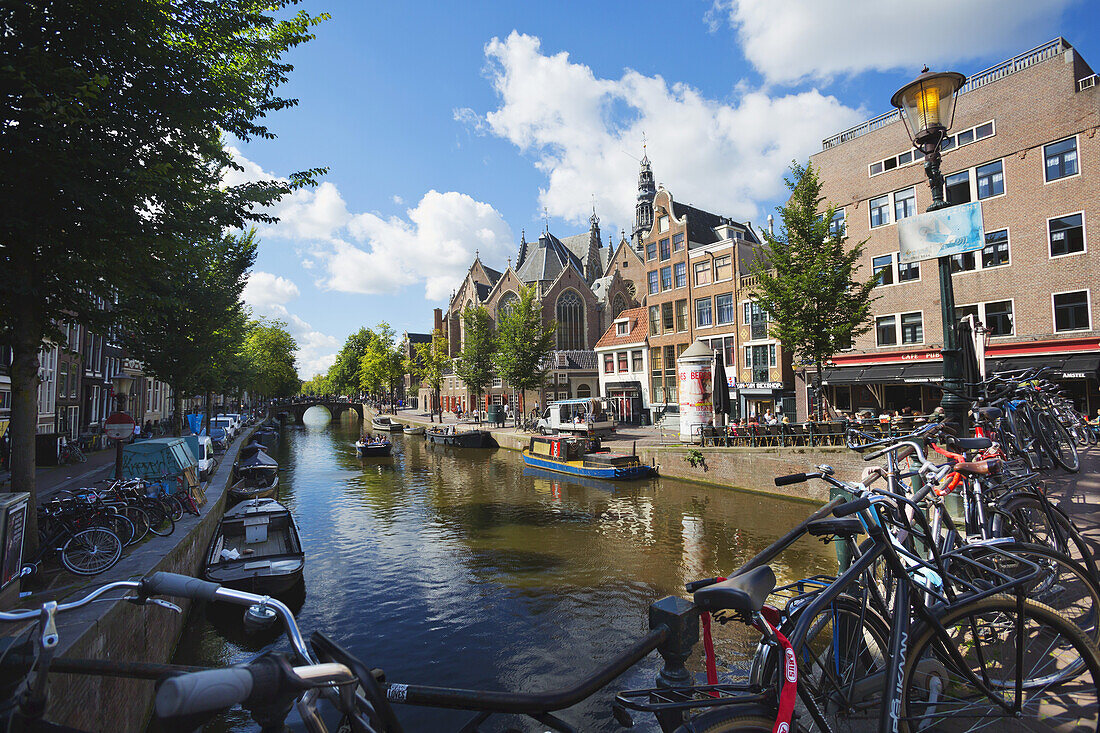 Gracht in Amsterdam mit der alten Kirche im Hintergrund rechts; Holland, Amsterdam