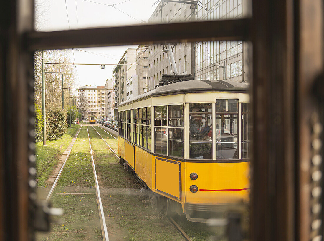 Eine leuchtend gelbe Straßenbahn, aus einem Fenster gesehen; Mailand, Lombardei, Italien