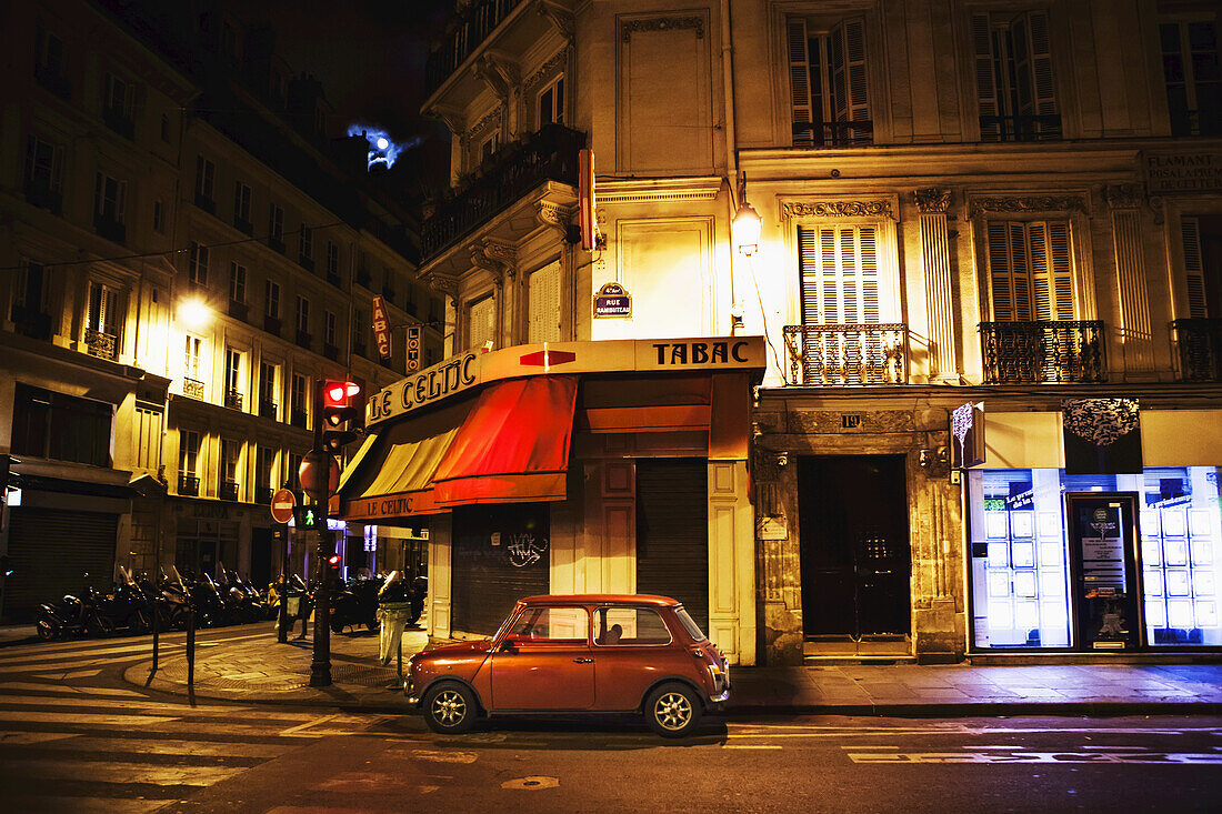 Stadtstraße mit rotem Auto; Paris, Frankreich.