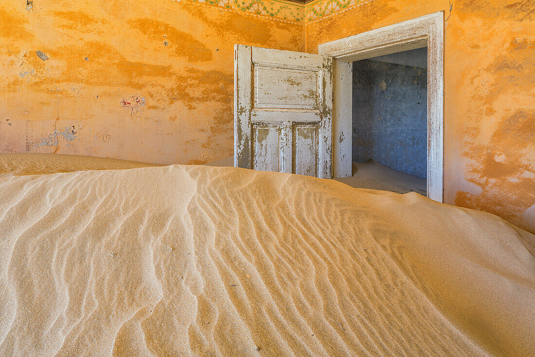 Sand in den Räumen eines farbenfrohen und verlassenen Hauses; Kolmanskop, Namibia
