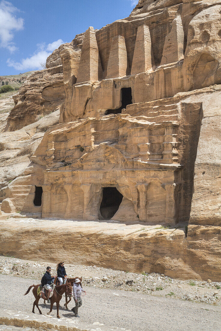 Touristen auf Pferden, Obeliskengrab (oberes Bauwerk), Bab As-Sig Triclinium (unteres Bauwerk); Petra, Jordanien.