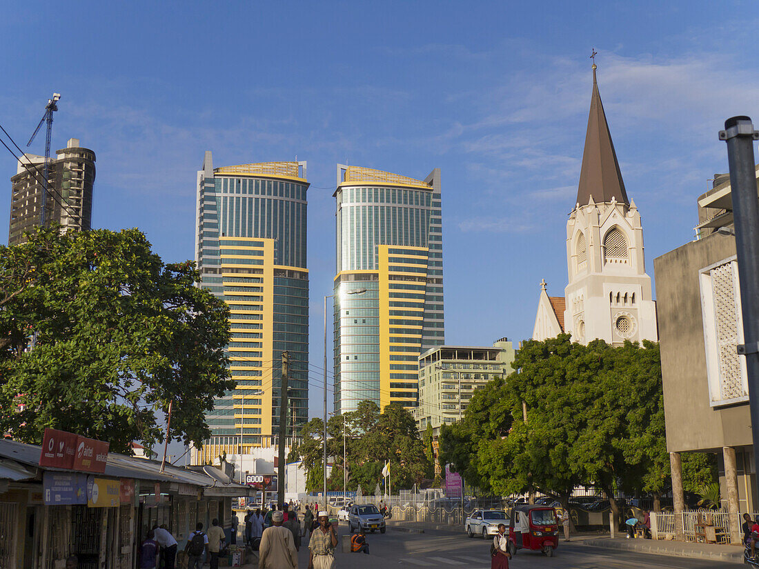 Pedestrians, St. Joseph's Cathedral, And Twin Buildings Against A Blue Sky; Dar Es Salaam, Tanzania