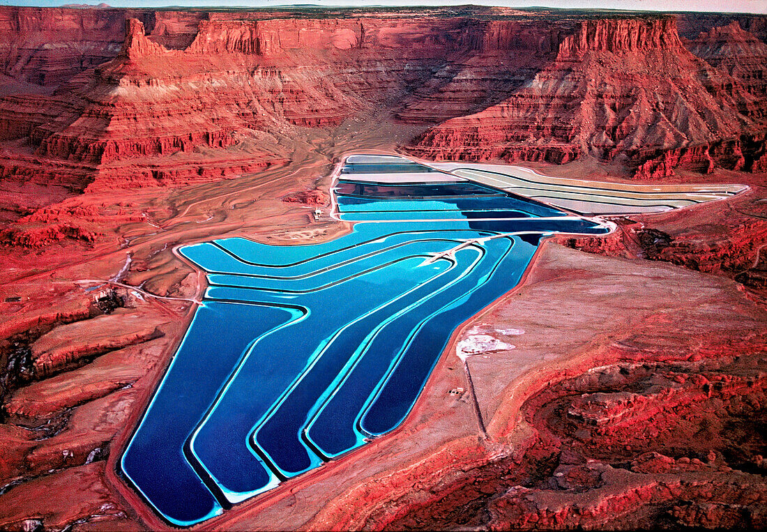 Aerial view of TexasGulf Potash Ponds which are solar evaporation ponds used in the process of mining potash. Potash, a water-soluble potassium salt  is extracted and blue dye is added to increase the rate of evaporation. It is mainly used in fertilizer products but also in the making of soap, glass, ceramics and batteries. The mine is currently owned and operated by Intredpid Potash Inc and the ponds cover 400 acres of land surrounded by sandstone cliffs and wilderness near Moab, Utah, USA; Utah, United States of America
