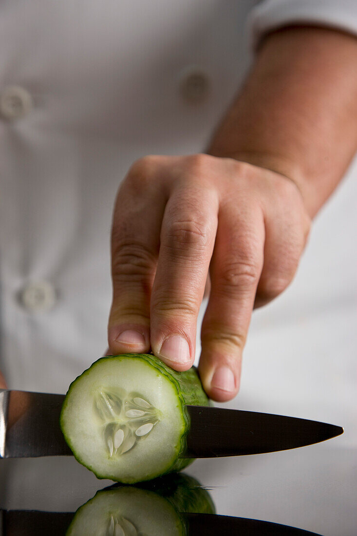 Close up of a chef hand slicing a cucumber