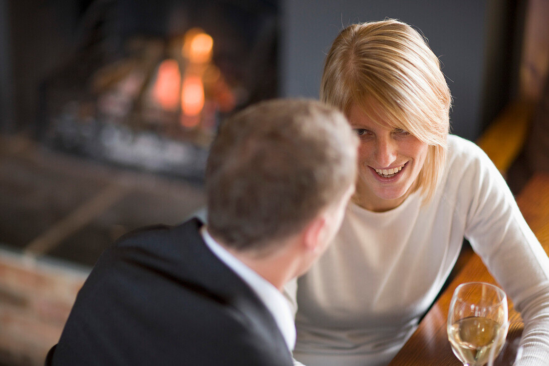 Pärchen sitzt am Kamin und trinkt Wein