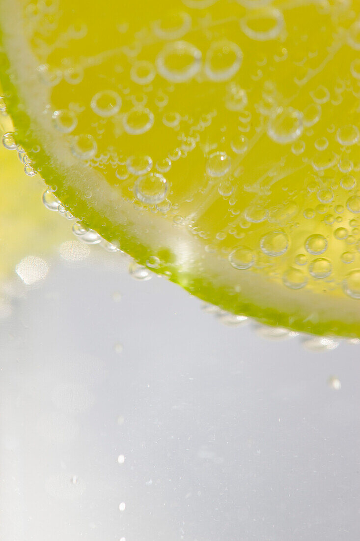 Extreme close up of a slice of lime floating in sparkling water