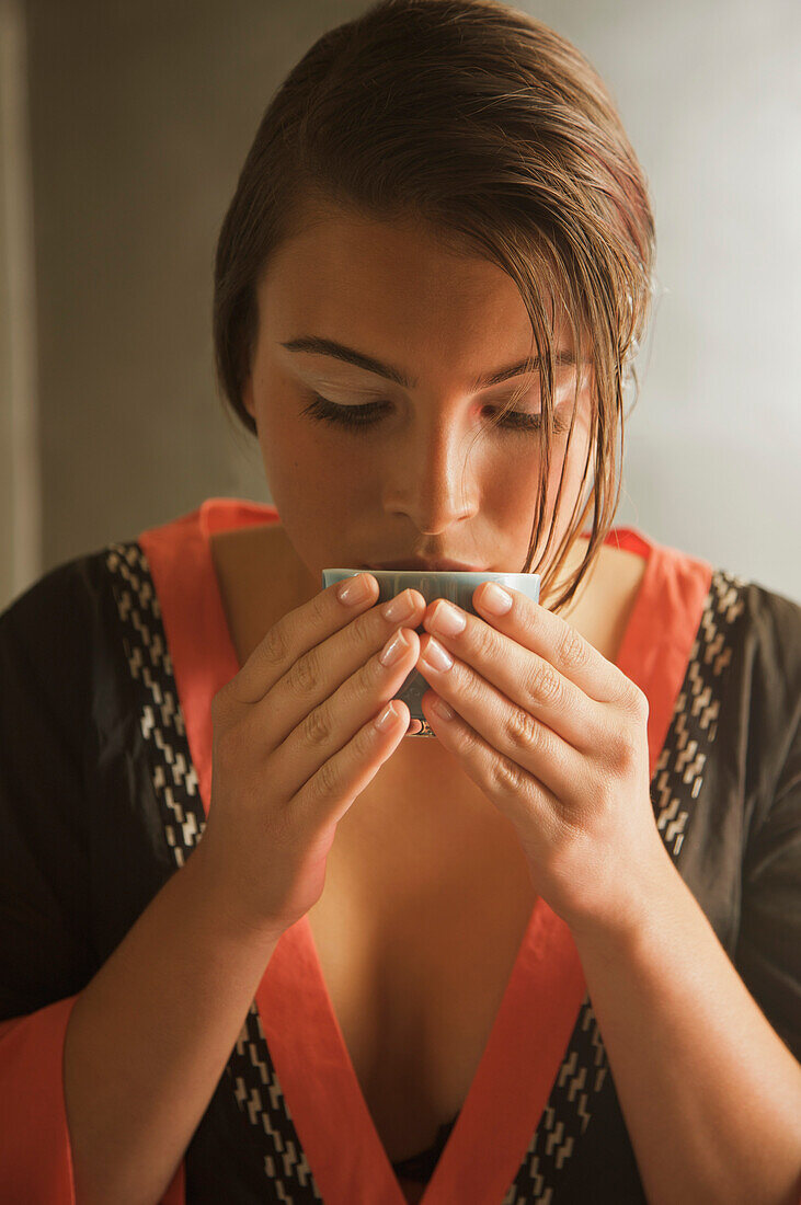 Young woman holding teacup and drinking green tea