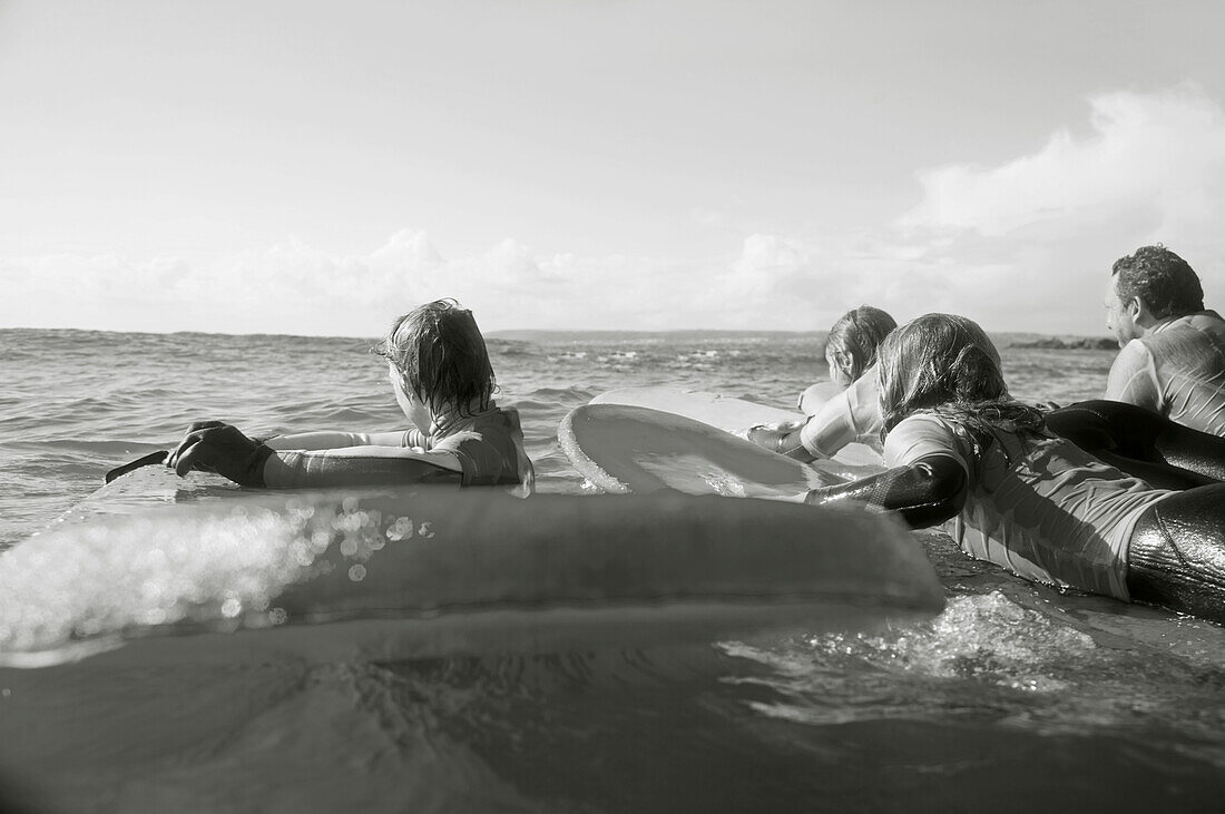 Rückenansicht von Surfern im Meer beim Paddeln