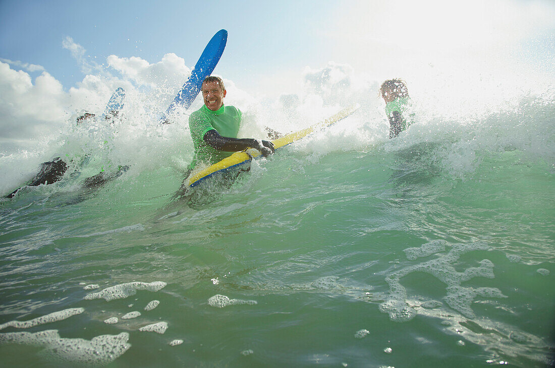 Lächelnder Surfer im Meer, der aus einer Welle kommt