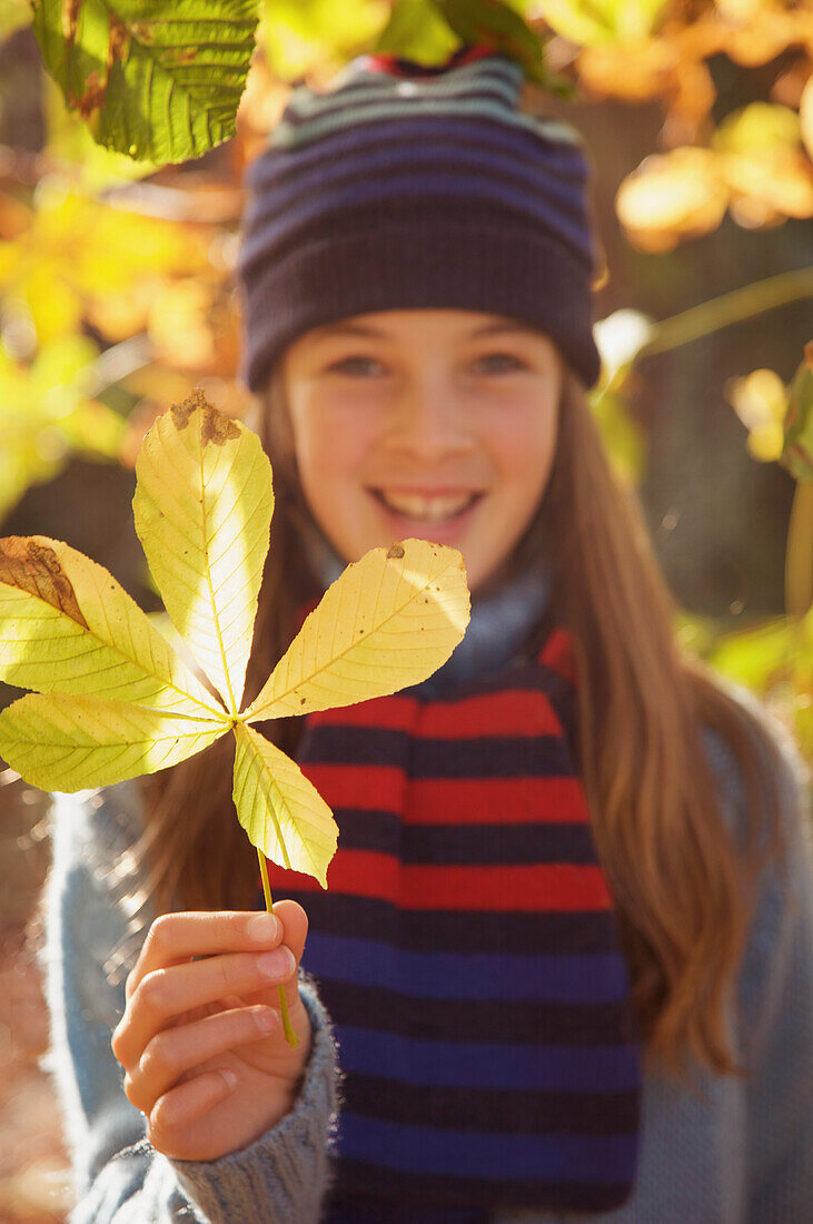 Smiling young girl holding a leaf