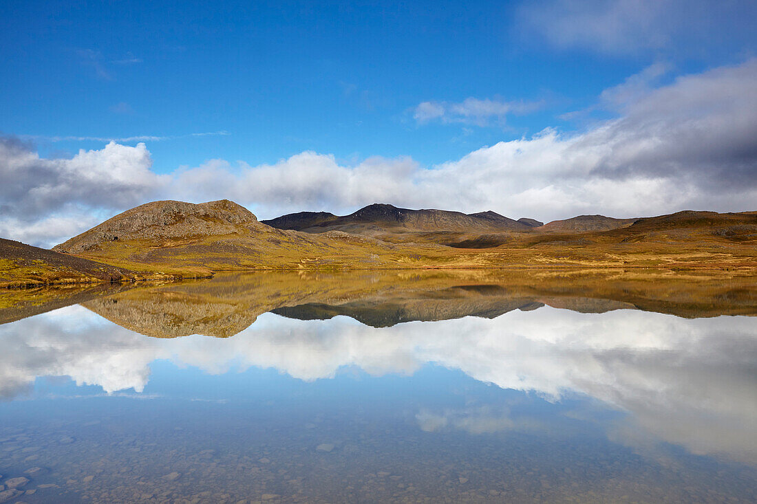 Landforms and clouds and their mirror reflection in a clear lake at Valafell mountain pass, near Olafsvik, Snaefellsnes peninsula, west coast of Iceland; Iceland