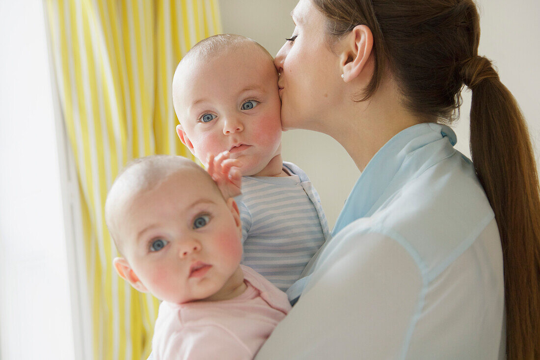 Mutter küsst Zwillingsbabys