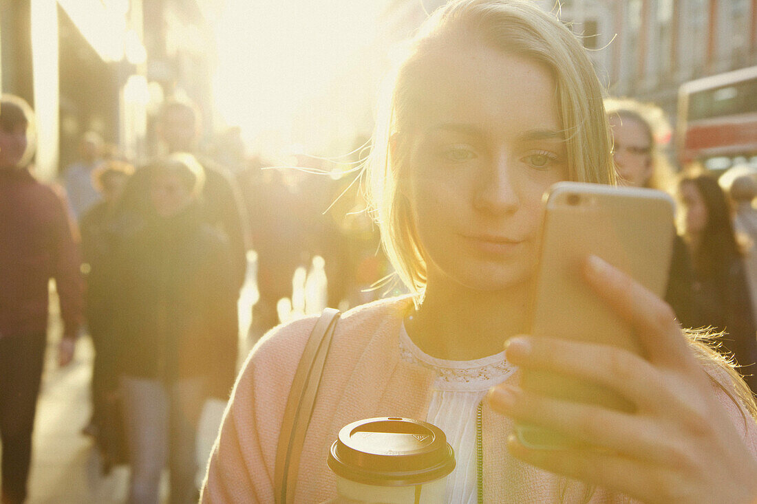 Junge Frau benutzt Smartphone auf einer Straße in der Stadt