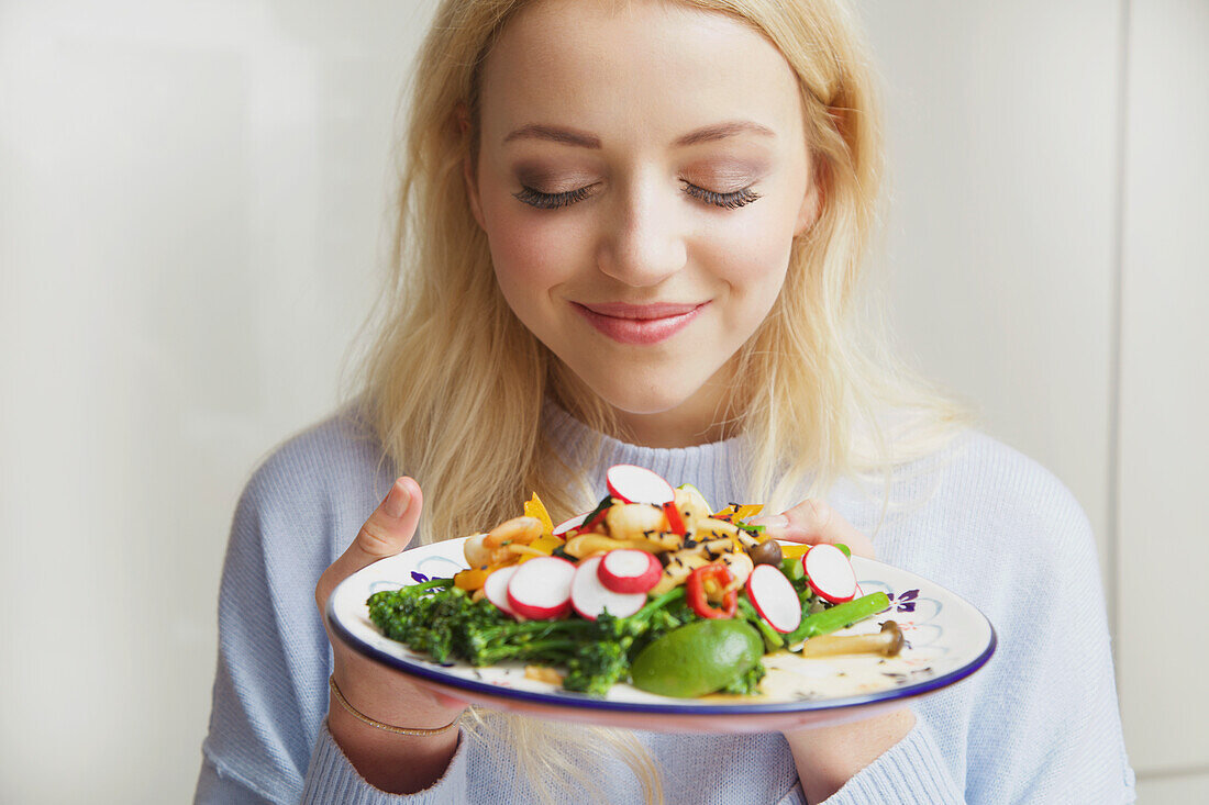 Smiling Woman Holding Plate with Stir Fry