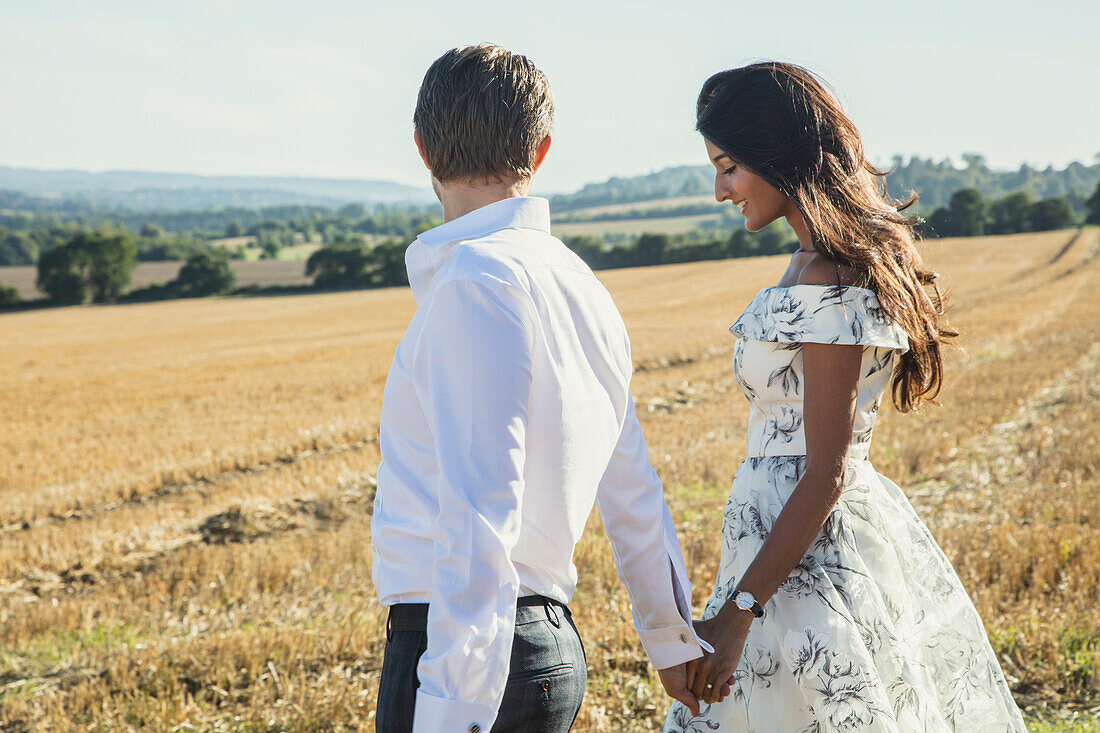 Couple Walking in a Field Holding Hands