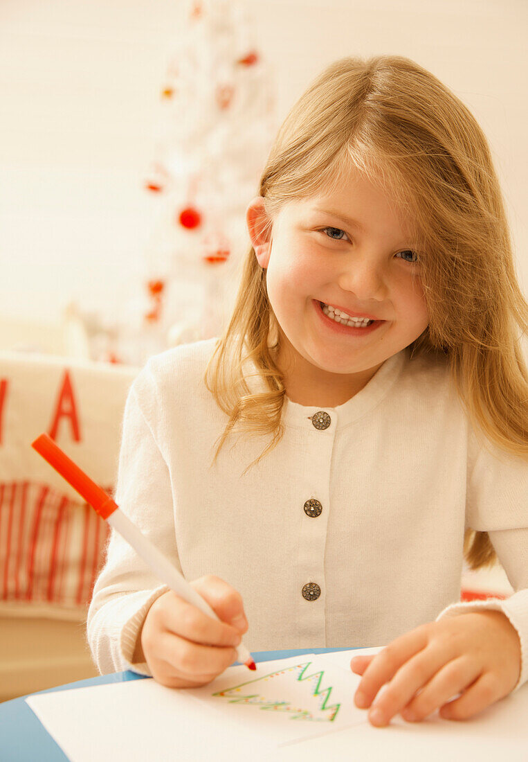 Lächelndes Mädchen schreibt einen Brief an den Weihnachtsmann