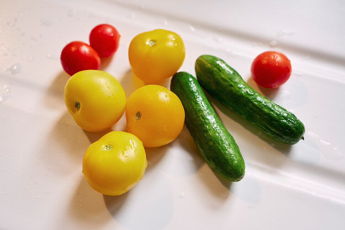 Nahaufnahme eines Stillebens mit frischen, feuchten Kirschtomaten und Gurken