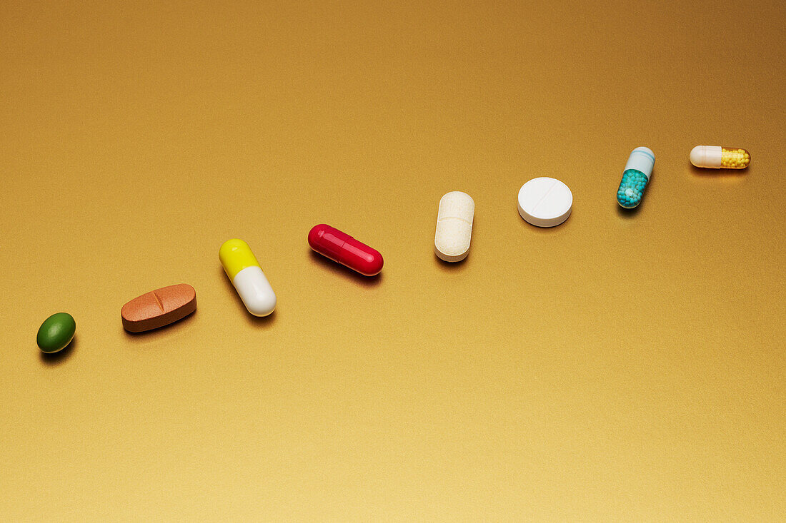 Stilleben Arrangement verschiedener Medikamente, Pillen und Kapseln auf gelbem Hintergrund