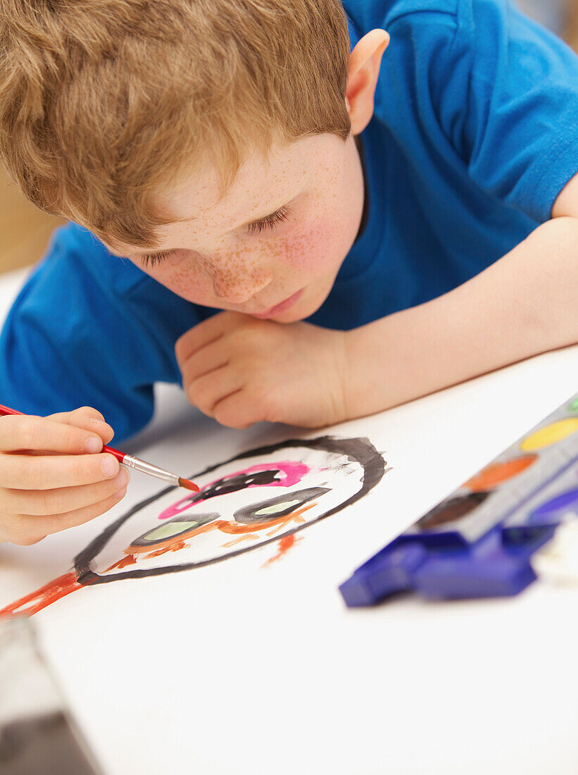 Young boy lying on floor painting with watercolors